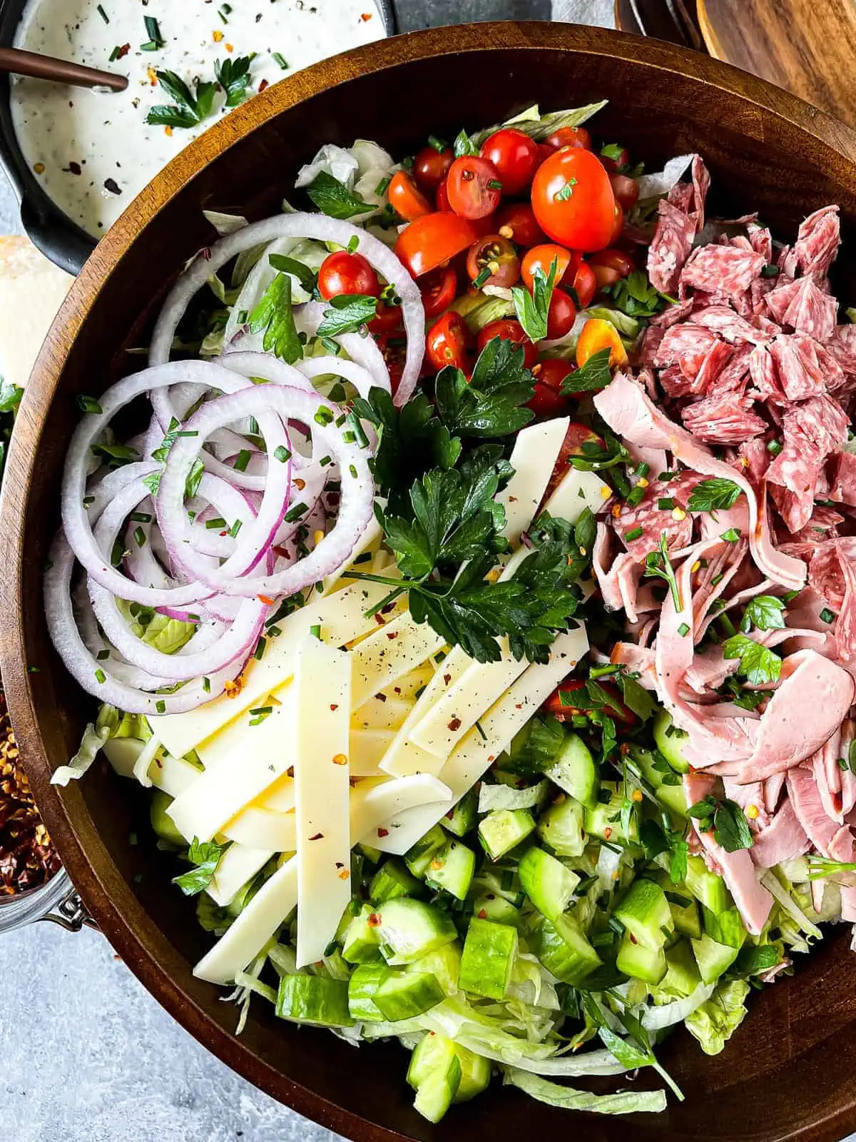 Overhead shot of a grinder salad with all the ingredients and dressing on the side