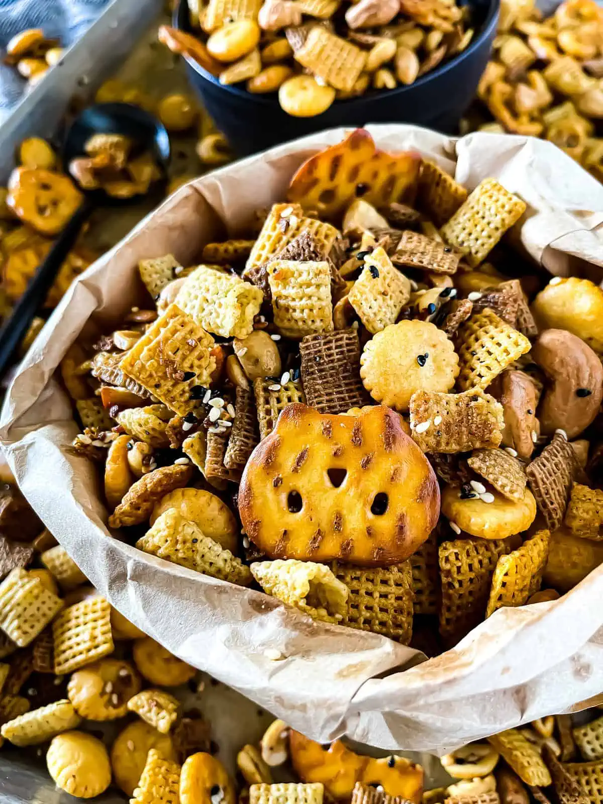 Picture of a bag of savory snack mix with close up of the pretzels, cereals, oyster crackers and the seasoning blend made from Everything But The Bagel Seasoning