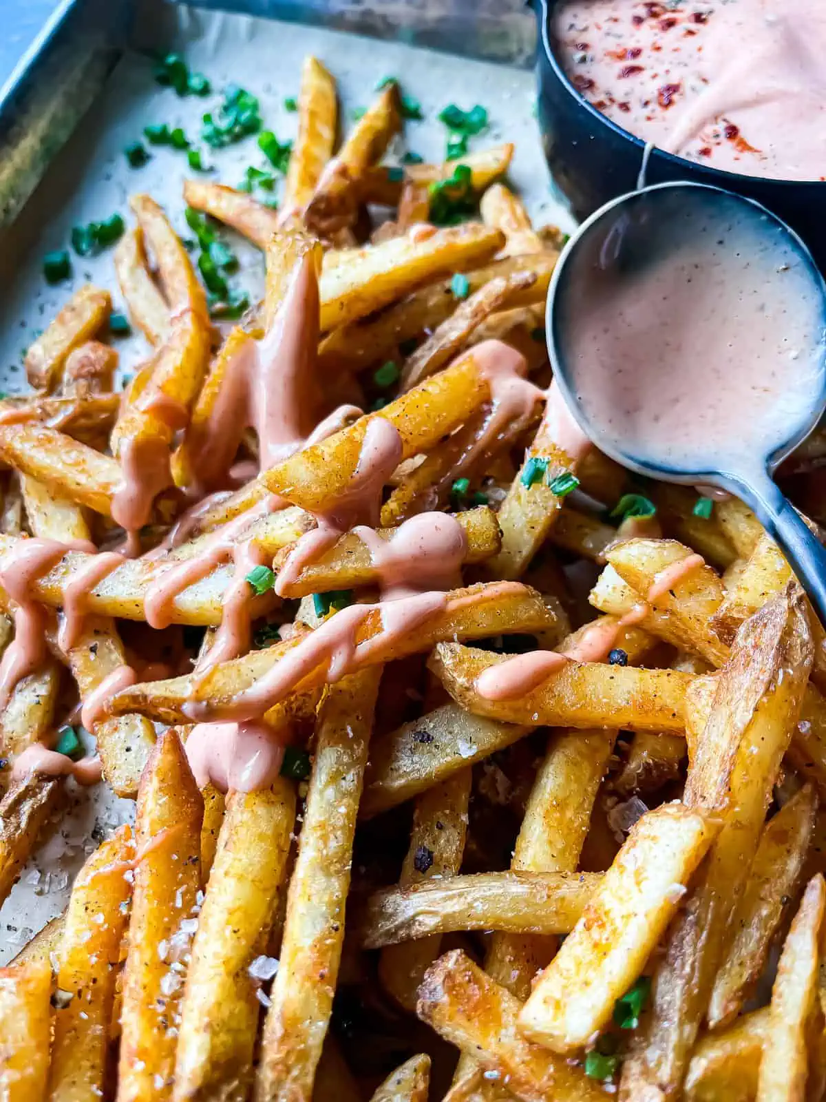 French fry sauce drizzled over a sheet pan of fries