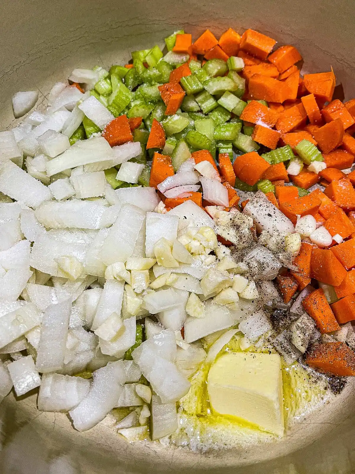 mirepoix - diced onions, carrots, celery, and garlic cooking with butter